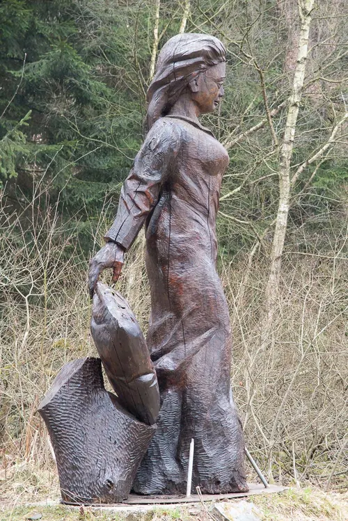 Holzskulptur der Frau Holle mit Kissen unter dem Arm